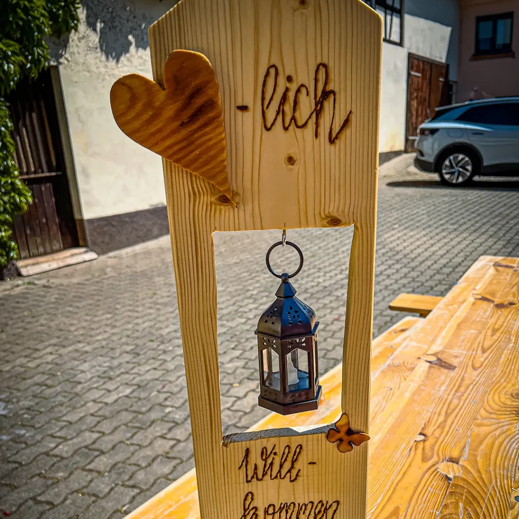 ein aus holz gebasteltes willkommens schild mit einer laterne darin