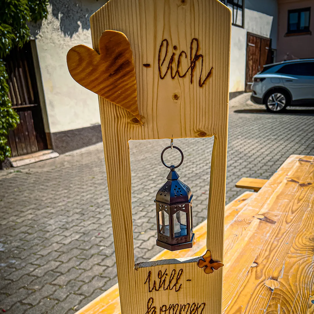 ein aus holz gebasteltes willkommens schild mit einer laterne darin