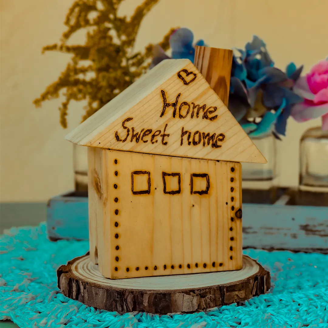 gebasteltes holzhaus mit der aufschrift home sweet home auf dem tisch vor dem laden mit dekoration im hintergrund