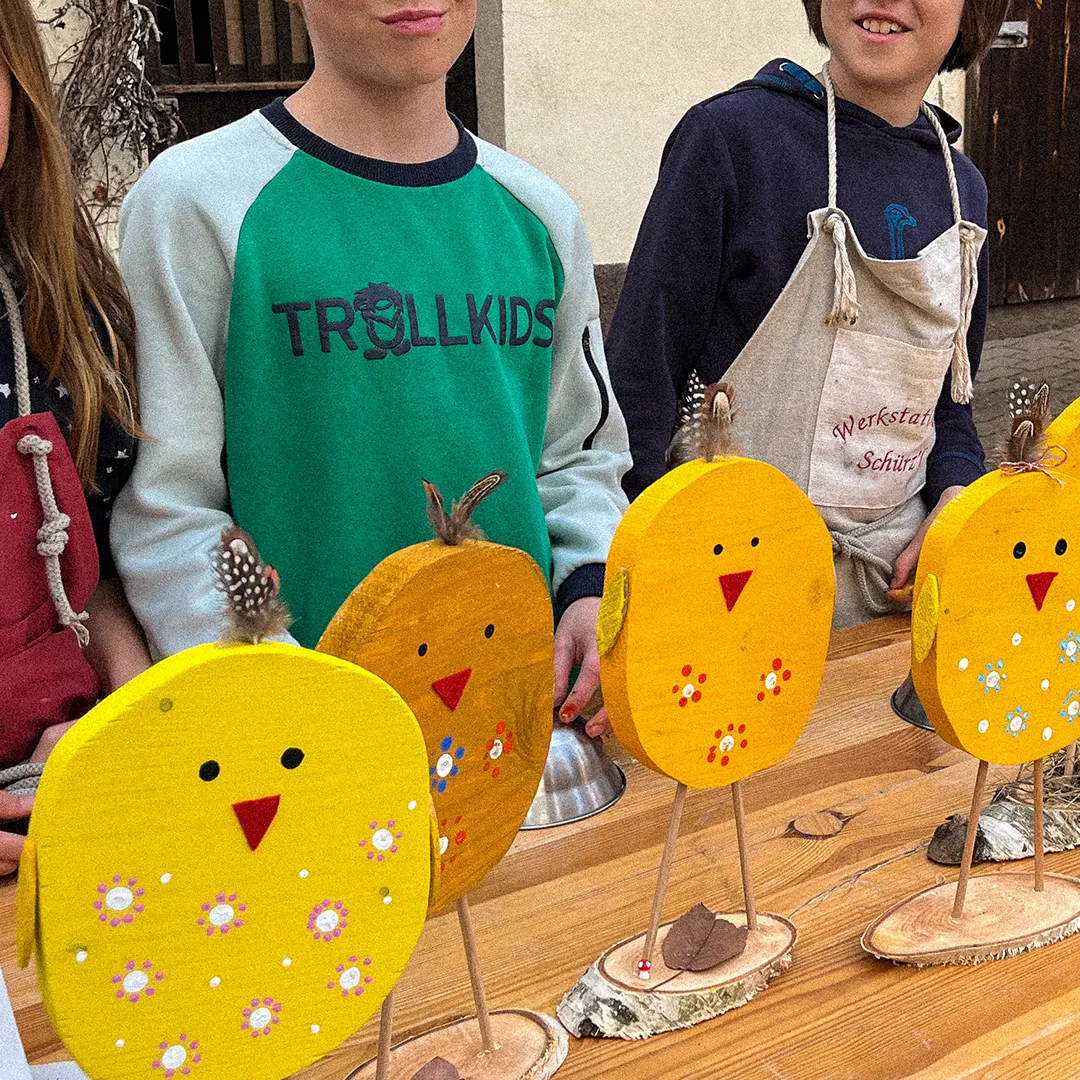 kinder praesentieren ihre gebastelten und mit farbe bemalten kuecken aus holz und freuen sich
