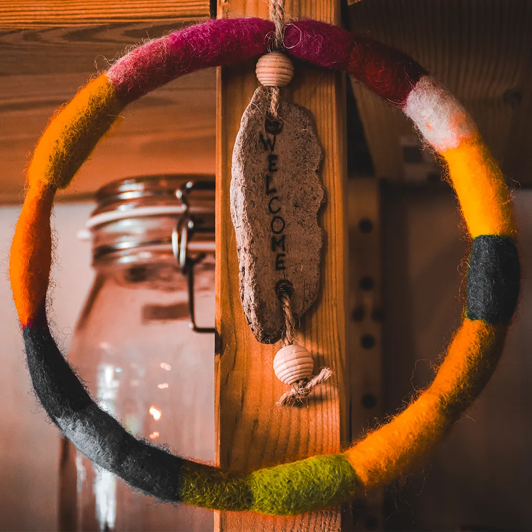 ring aus buntem filz mit flachem stein in der mitte auf dem welcome steht