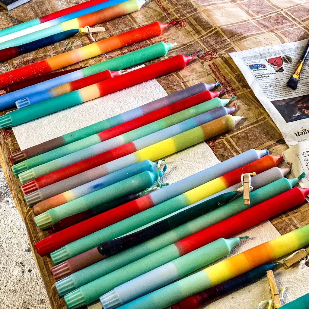 viele bunte kerzen auf einem tisch die von kindern selbst gebastelt wurden
