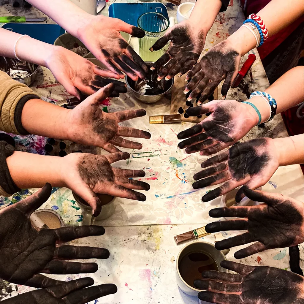 viele kinder ihre haende praesentieren nachdem sie mit schwarzer farbe bemalt sind