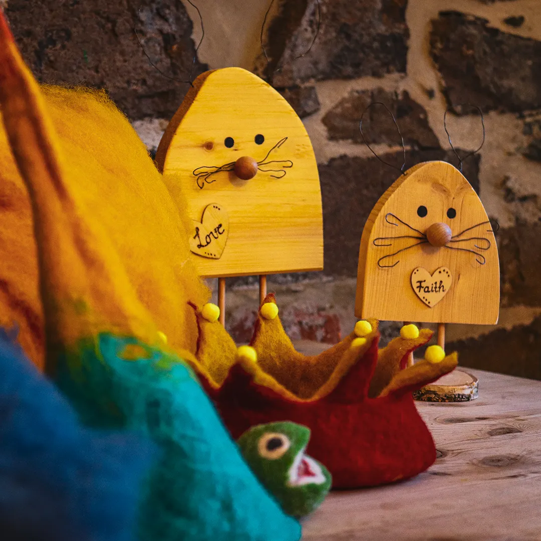 zwei holz hasen mit der aufschrift love und faith hinter einem haufen aus filz