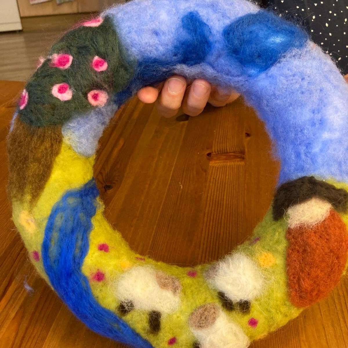 ein Kind zeigt seinen fertigen Filzkranz in die Kamera