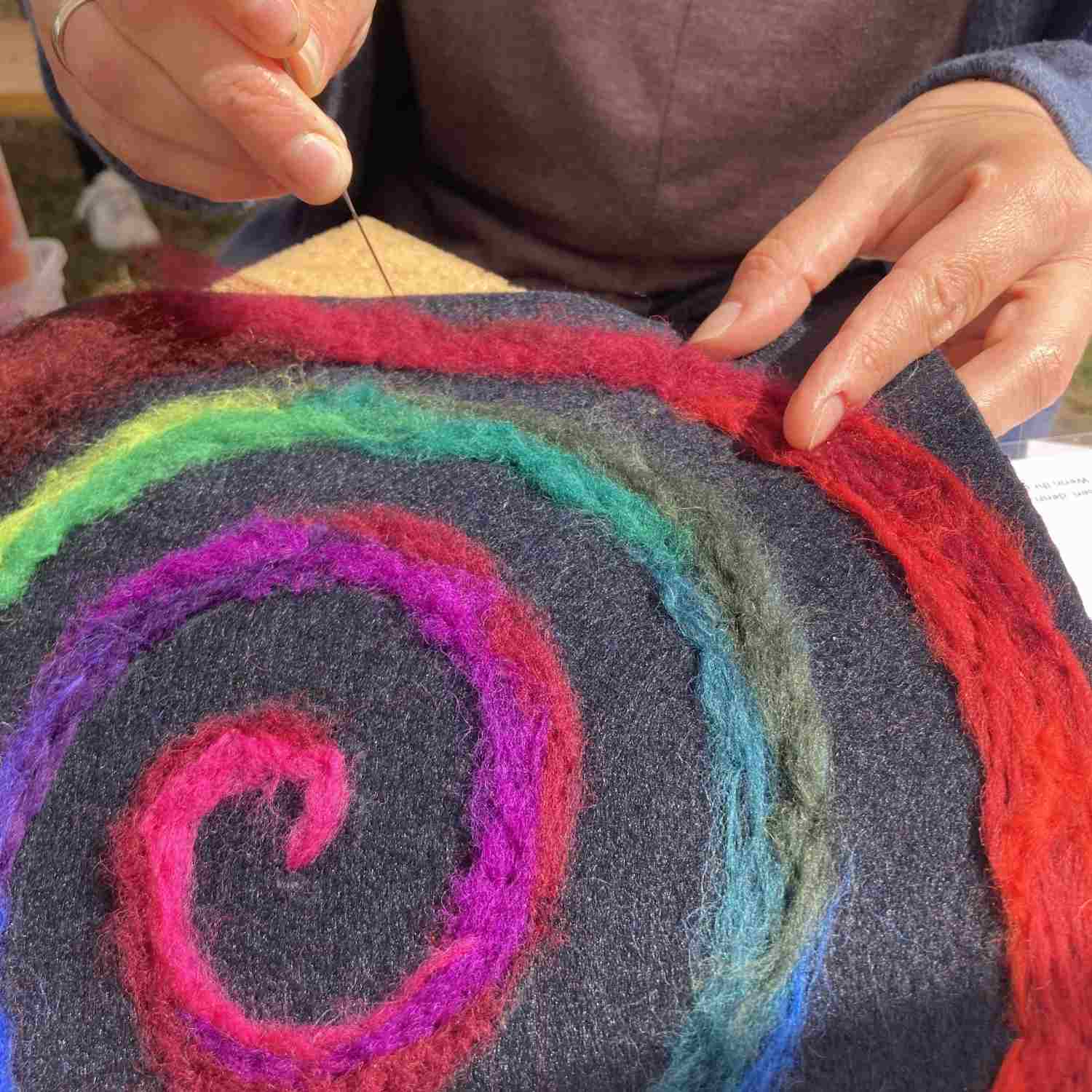 bunter kringel aus filz wird von einer Frau bearbeitet